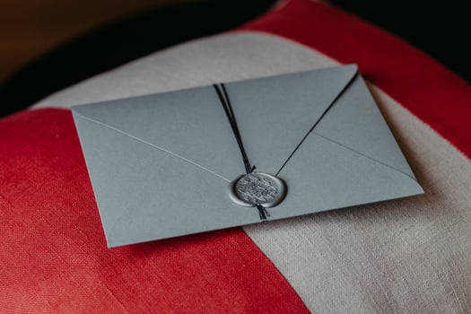 Indoor shot of elegant grey paper invitation card lies on sofa pillow. Invitation for anniversary or wedding. Decoration photo