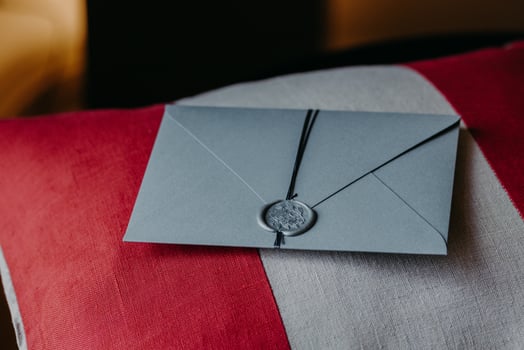 Grey invitation card for wedding or special occasion on red and white pillow. Wedding decor. Horizontal view. Holiday concept photo