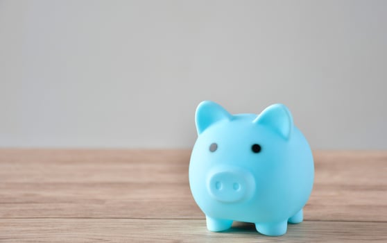 A blue piggy bank and a coin on a wooden table to save money . photo
