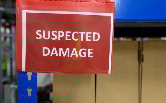 A shelf with packages and a sign saying SUSPECTED DAMAGE photo