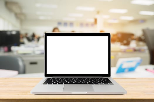 Laptop with blank screen on desk table with blur office interior background photo