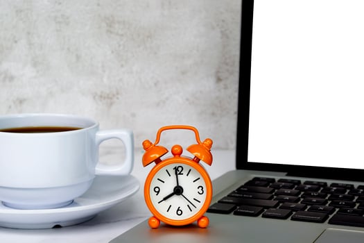 Alarm clock on laptop with coffee cup on a table. The clock set at 8 o'clock. photo