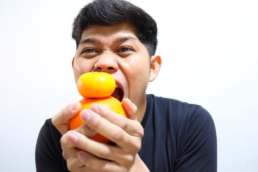 Attractive asian man eating oranges. Isolated on white background photo