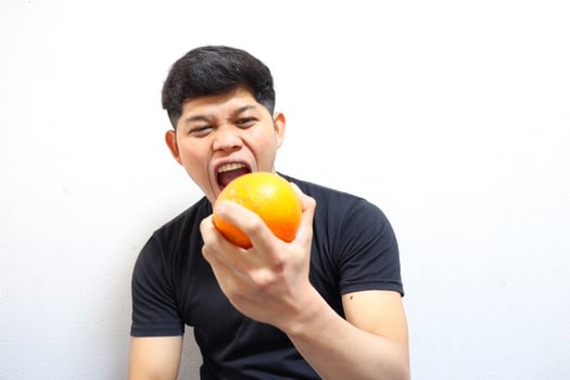 Attractive asian man eating oranges. Isolated on white background photo