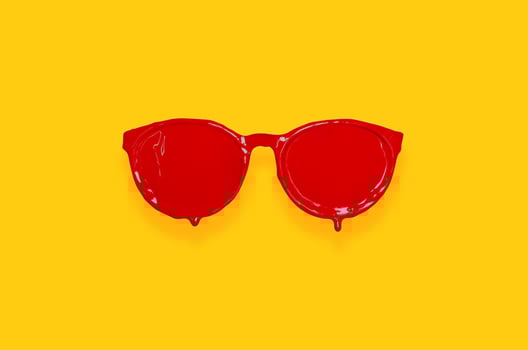 Red poster color painted on sunglasses with yellow background. photo