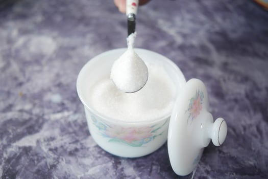 white sugar and spoon in a container on black background, photo