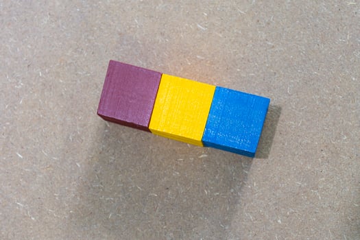 Three colorful wooden cubes against wooden background. Flat lay. Copy Space. photo
