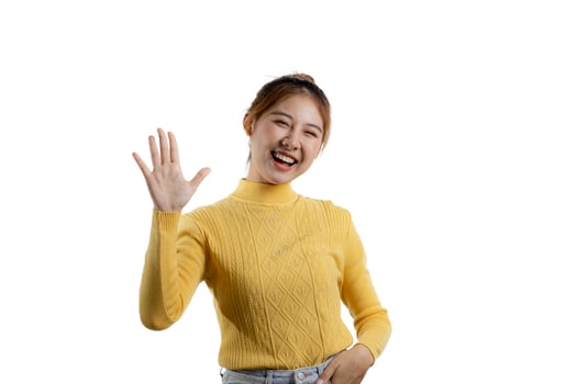 Portrait of a beautiful Asian woman in a yellow shirt standing with her hands up in joy. portrait concept used for advertisement and signage, isolated over the blank background, copy space. photo