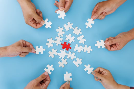 Hands of diverse people assembling jigsaw puzzle, team put pieces together searching for right match, help support in teamwork to find common solution concept, top close up view photo