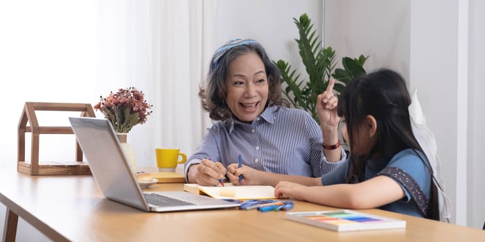 Asian grandmather teach granddaughter drawing and doing homework at home. photo