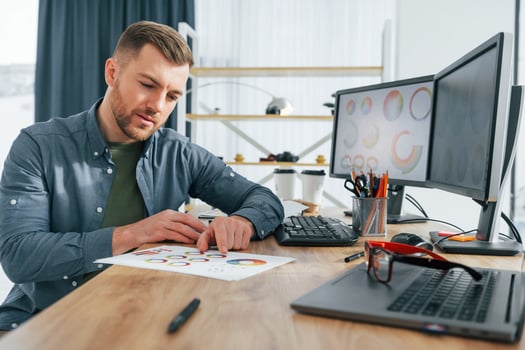 Paper with different colors. Male designer working in the office by using PC photo