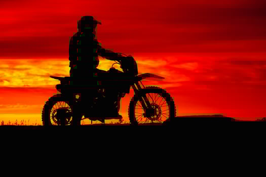 black silhouette of biker with motobike on red sunset sky background photo