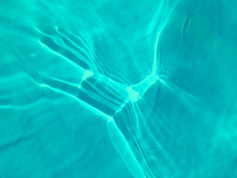Defocus blurred transparent blue colored clear calm water surface texture with splashes and bubbles. Trendy abstract nature background. Water waves in sunlight. Blue water background. photo
