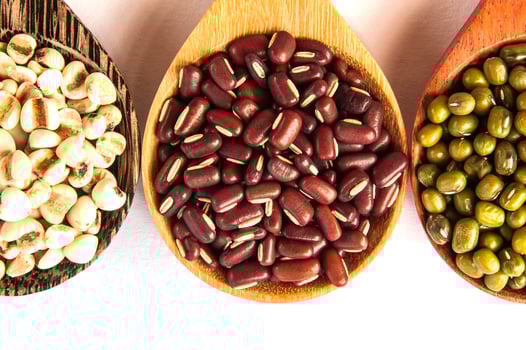 Legumes in a wooden spoon placed on a white background photo