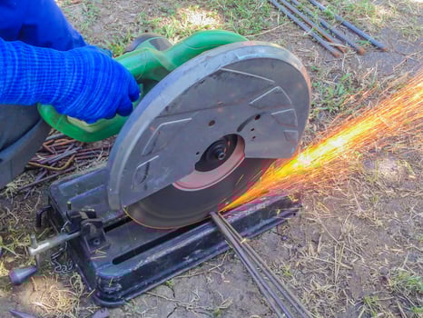 Worker's hand cutting steel rod by a machine in construction site photo