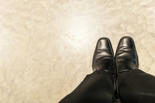 Top view of old black pants and leather shoes of relax sitting businessman on cement floor. Photo is focused at shoes.