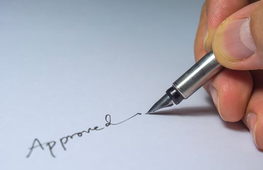 Closeup of approved signature with fingers and pen, light bulb from left side in the dark room photo