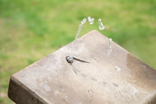 Stream of water pours from the outdoor water fountain in the park photo