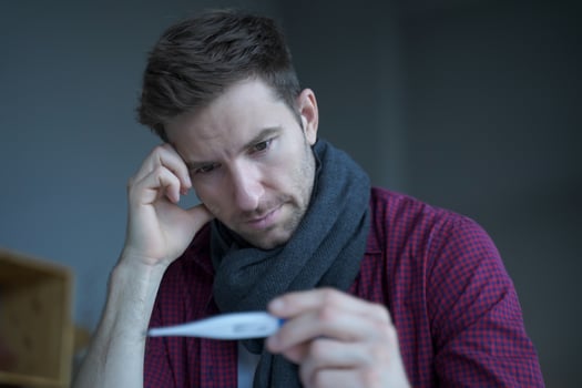 Sick unhealthy German man office worker looking at thermometer, suffer of flu influenza photo