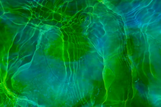 Defocus blurred transparent green colored clear calm water surface texture with splashes and bubbles. Trendy abstract nature background. Water waves in sunlight. Green water background. photo