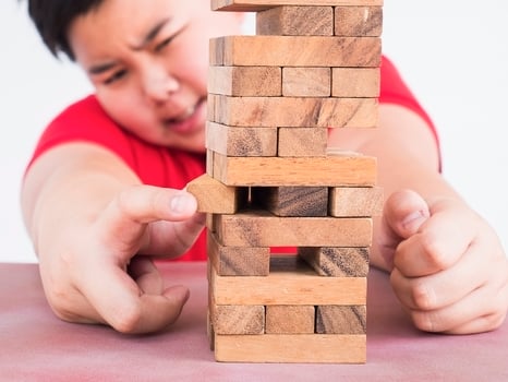 Asian kid is playing jenga, a wood blocks tower game for practicing physical and mental skill photo