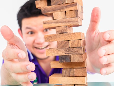 Asian guy is playing jenga, a wood blocks tower game for practicing physical and mental skill photo
