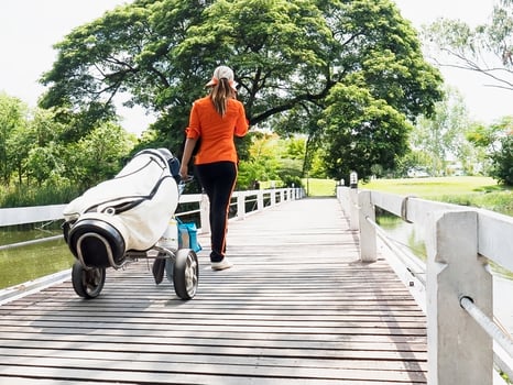 Golf caddy is walking with her trolley photo