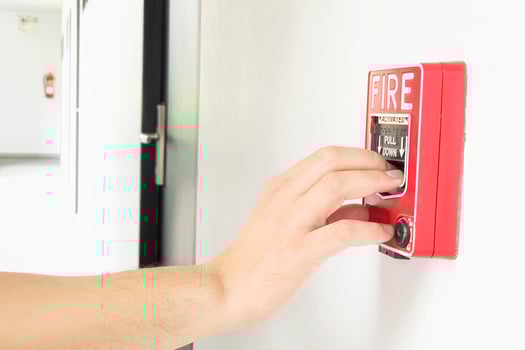 Man is reaching his hand to push fire alarm hand station photo