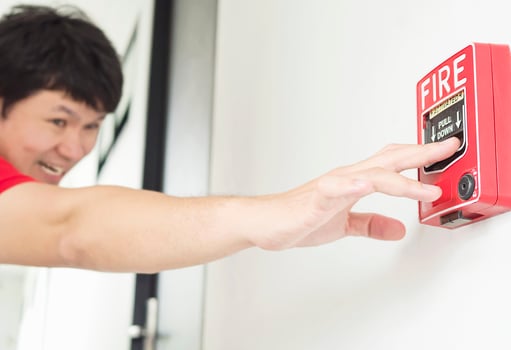 Man is reaching his hand to push fire alarm hand station photo