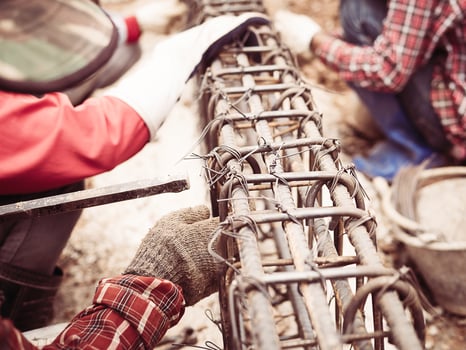 Vintage style photo of construction workers are installing steel rods in reinforced concrete beam