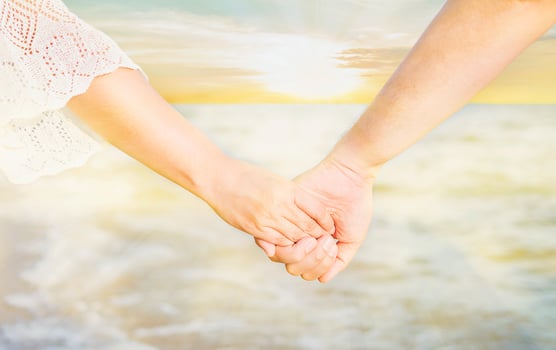 Asian couple is holding hand near to the sea with warm sun light sky photo