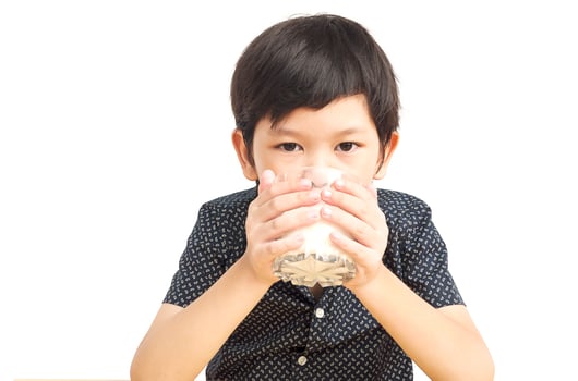 Asian boy is drinking a glass of milk over white background photo