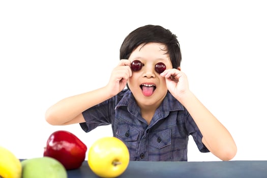 Asian healthy boy showing happy expression with variety colorful fruit and vegetable over white background photo