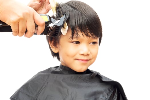 A boy is cut his hair by hair dresser isolated over white background photo
