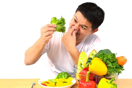 Asian man showing dislike expression of fresh colorful vegetables isolated over white background photo
