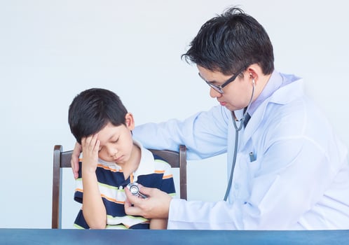 Sick asian boy being examined by male doctor over white background photo