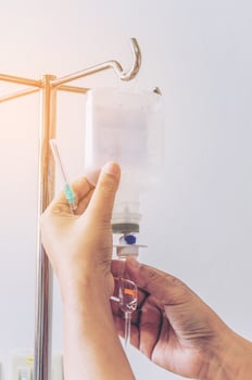 Nurse's hands is removing IV fluid drip from metal stand in hospital photo
