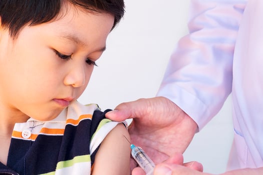 Sick Asian boy being treated by male doctor over white background photo