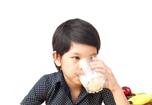 Asian boy is drinking a glass of milk over white background photo