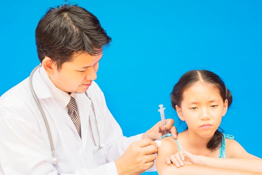 Sick Asian girl is being treated by male doctor over blue background photo