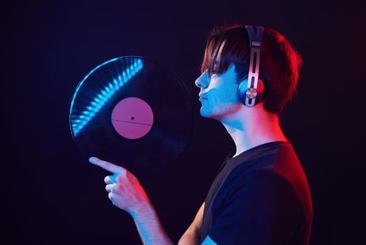 With vinyl record in hands. Man standing in the studio with neon light photo