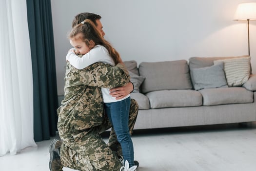Finally meet each other. Soldier in uniform is at home with his little daughter photo