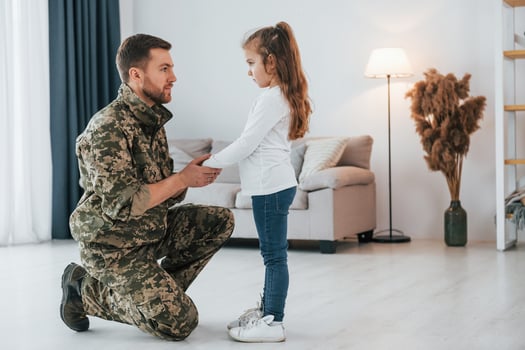 Side view. Soldier in uniform is at home with his little daughter photo