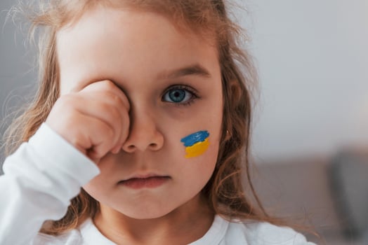 Innocent child is crying. Portrait of little girl with Ukrainian flag make up on the face photo