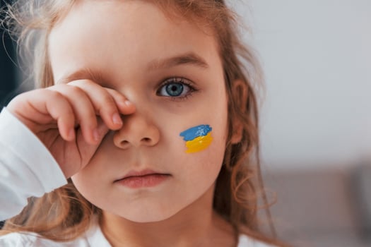 Innocent child is crying. Portrait of little girl with Ukrainian flag make up on the face photo