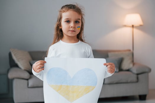 Little girl holding banner with image of heat in Ukrainian flag color photo