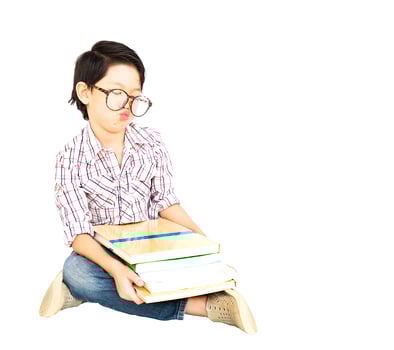 7 years old Asian boy is feeling Bored with a pile of book isolated over white. photo