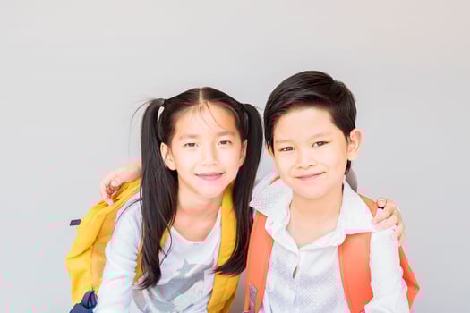 Lovely Asian couple school kids, 7 and 10 years old, over gray background photo
