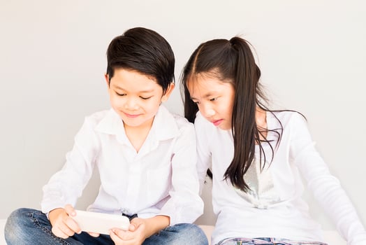 Lovely Asian couple school kids are taking selfie, 7 and 10 years old, over gray background photo
