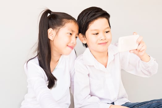 Lovely Asian couple school kids are taking selfie, 7 and 10 years old, over gray background photo